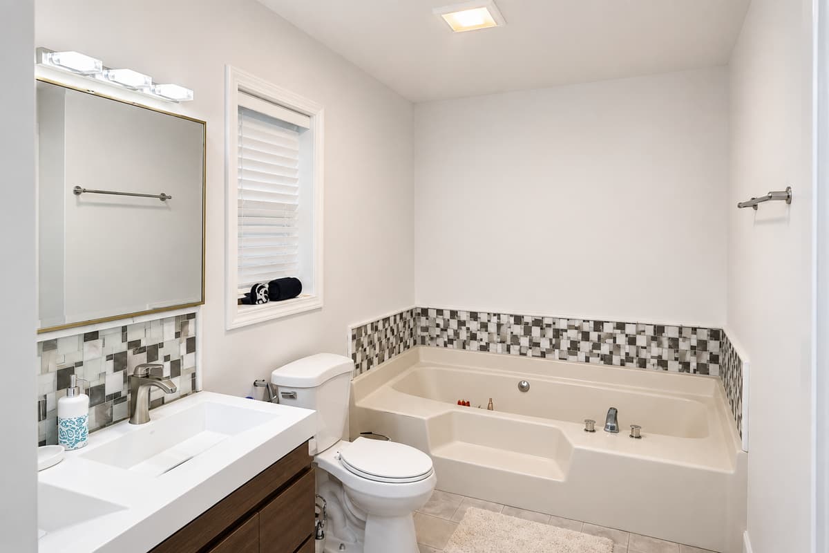 Ensuite master bathroom with soaking tub and mosaic tile accents