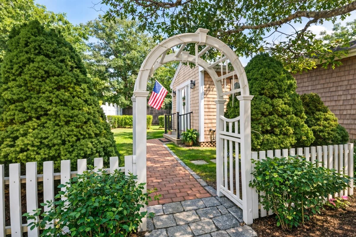 Charming arbor entrance with picket fence and brick pathway