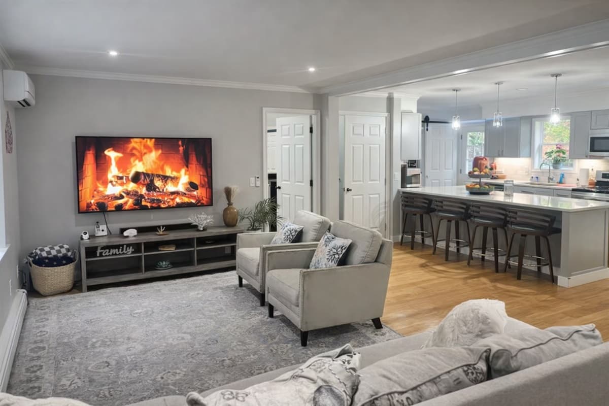 Open-plan living area with fireplace, large smart TV, and island seating