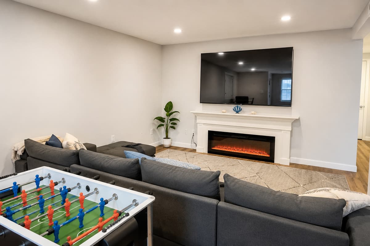 Basement living room with sectional, large smart TV, and electric fireplace